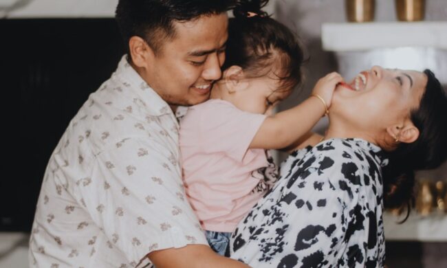 Mom and dad hugging child