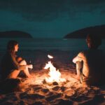 Couple sitting at campfire at night