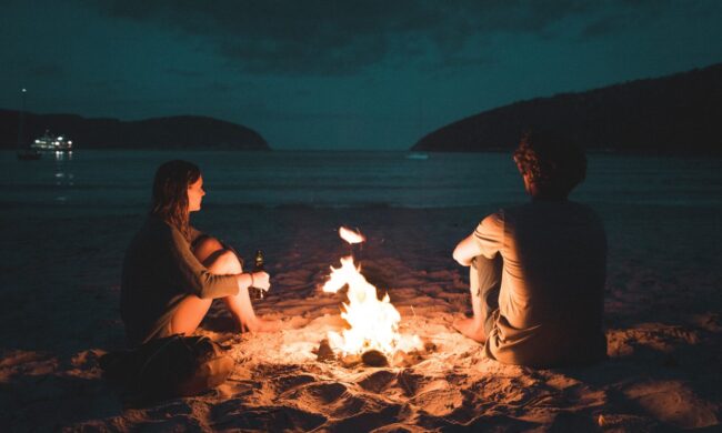 Couple sitting at campfire at night