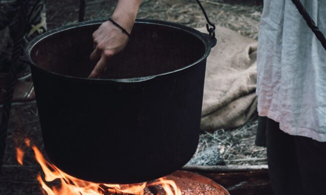 woman tending cauldron over fire
